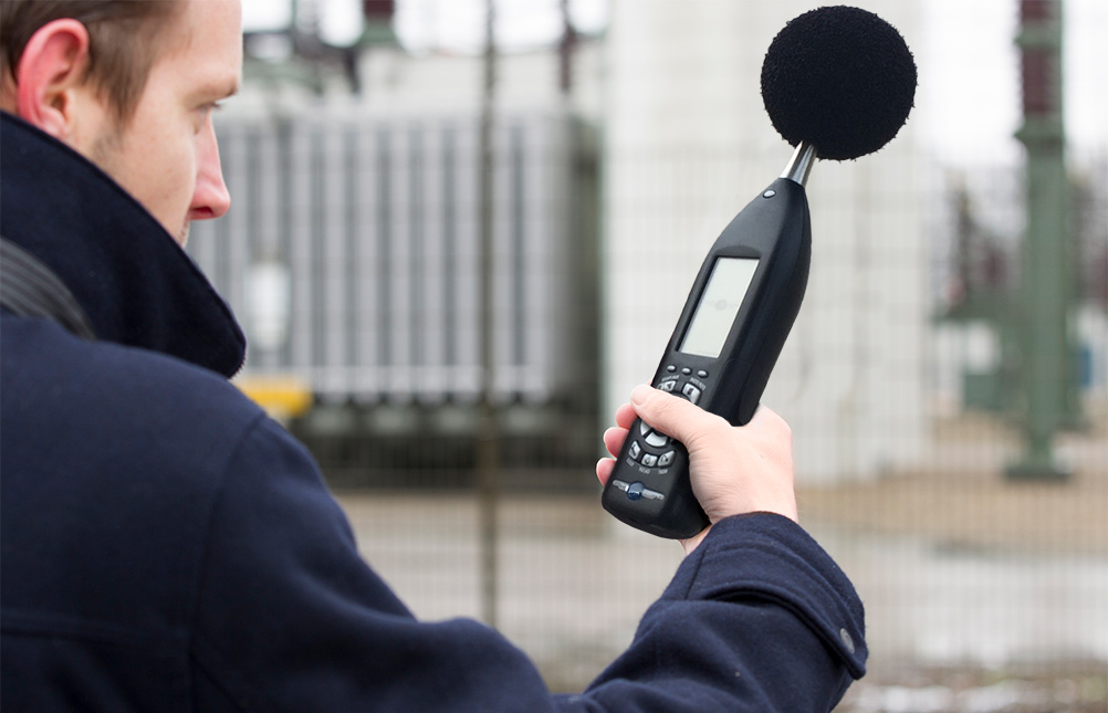 Acoustician measuring sound at an industrial worksite.